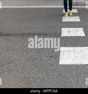 Close-up of woman wearing sneakers crossing street Stock Photo