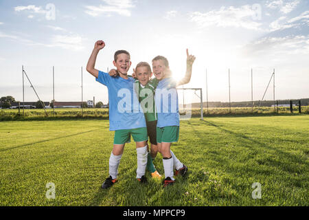 Young football players cheering on football ground Stock Photo