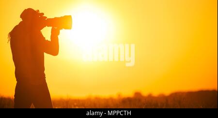 Nature Photographer Taking Pictures at the Sunset. Panoramic Photo. Stock Photo