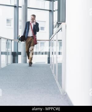 Smiling businessman holding skateboard and  talking on cell phone Stock Photo