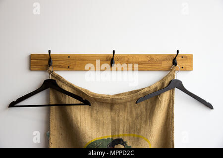 Hangers for clothes hang on hook against the white walls and burlap Stock Photo