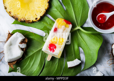 Pina Colada popsicle with candied cherries and pineapple on leaf Stock Photo