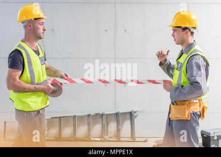 Construction workers using tape on construction site Stock Photo