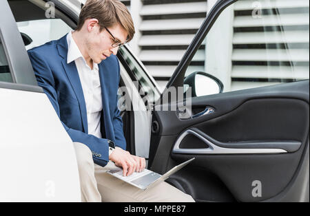 Businessman sitting in car using laptop Stock Photo