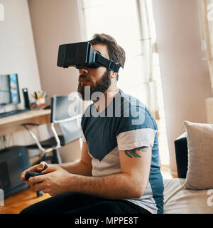 Man wearing virtual reality glasses at home playing computer game Stock Photo