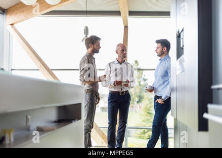 Three businessmen talking during coffee break Stock Photo