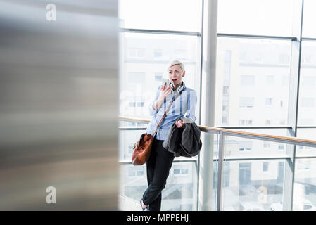 Woman in office building using cell phone Stock Photo