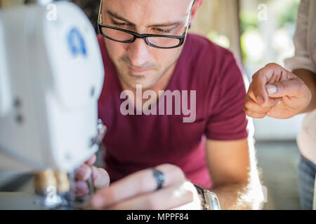 Close-up of man using sewing machine Stock Photo