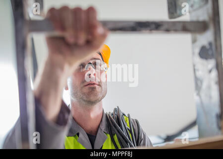 Close-up of construction worker climbing ladder Stock Photo