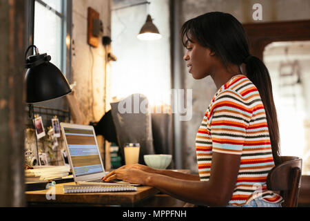 Young woman sitting at desk in a loft working on laptop Stock Photo