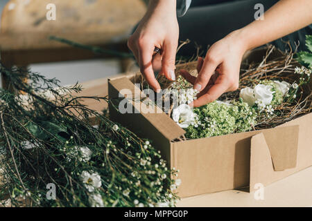 Woman's hands arranging flowers in a box, close-up Stock Photo