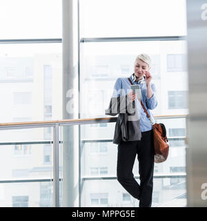 Smiling woman in office building using cell phone Stock Photo