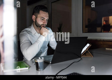 Businessman working on laptop in office at night Stock Photo