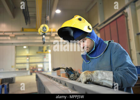 Welder checking metal surface in factory Stock Photo