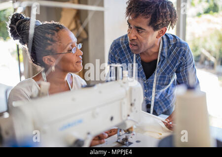 Fashion designer talking to seamstress in studio Stock Photo