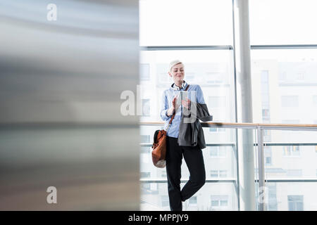 Smiling woman in office building using cell phone Stock Photo