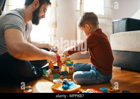 Father and son sitting on the floor  playing together with building bricks Stock Photo