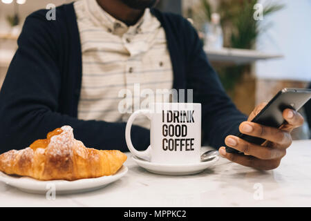 https://l450v.alamy.com/450v/mppkc2/close-up-of-man-with-croissant-and-cup-of-coffee-in-a-cafe-using-cell-phone-mppkc2.jpg