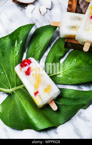 Pina Colada popsicle with candied cherries and pineapple on leaf Stock Photo