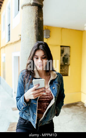 Young woman in a town checking her smartphone Stock Photo