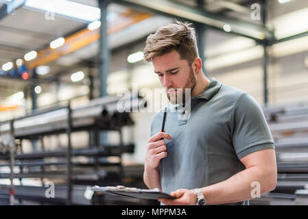 Man writing on clipboard on factory shop floor Stock Photo
