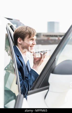 Smiling businessman using smartphone in car Stock Photo