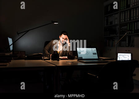 Businessman working in office at night Stock Photo