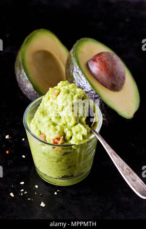 Glass of Guacamole and sliced avocado Stock Photo