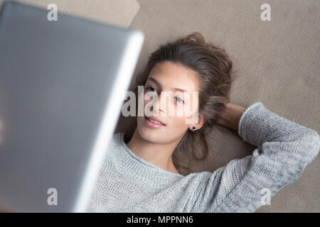Woman lying on couch using tablet Stock Photo
