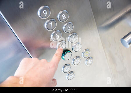 Finger presses on third floor of  modern office building elevator metal Stock Photo