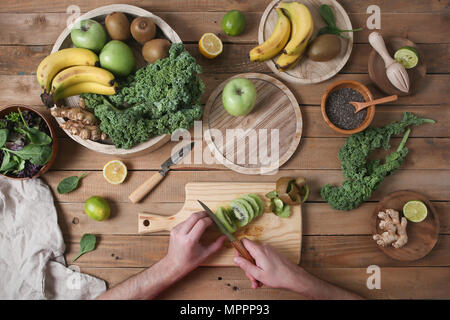 Man preparing green smoothie slicing kiwi Stock Photo