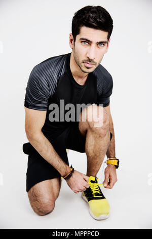 Portrait of young man wearing sportswear tying his shoe Stock Photo