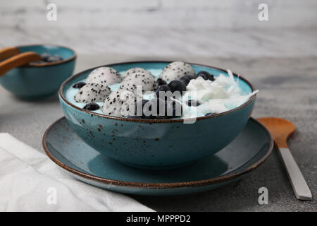 Blue smoothie bowl with grated coconut, blueberries and dragon fruit balls Stock Photo