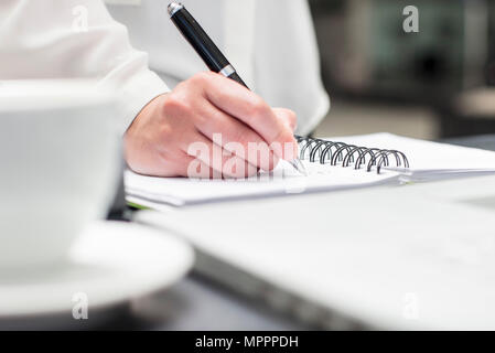 Woman making notes in diary Stock Photo