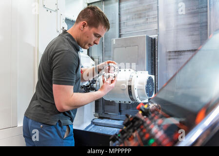 Man examining workpiece at machine in factory Stock Photo