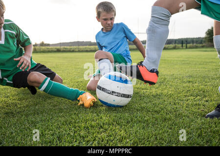 Young football players tackling on football ground Stock Photo