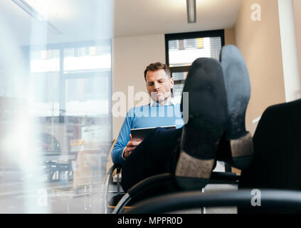 Casual businessman using tablet in office Stock Photo
