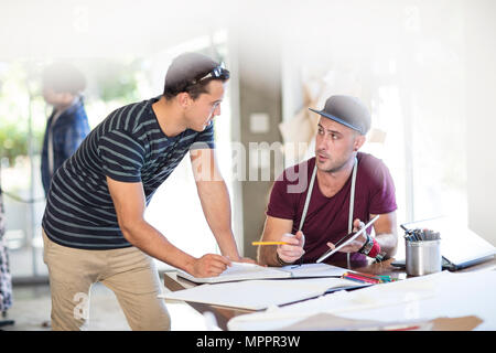 Two fashion designers talking and taking notes in studio Stock Photo