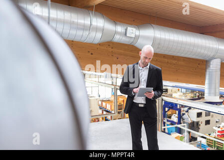 Businessman using tablet in modern factory Stock Photo