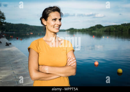 Portrait of smiling woman standing on jetty at a lake Stock Photo