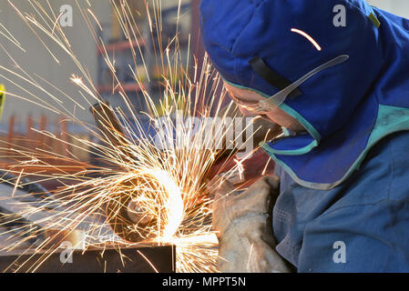 Worker using angle grinder in factory Stock Photo