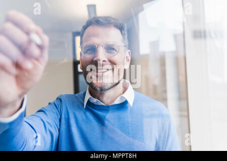Confident businessman writing on glass pane Stock Photo