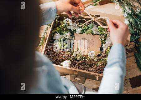Woman arranging flowers in a box, partial view Stock Photo