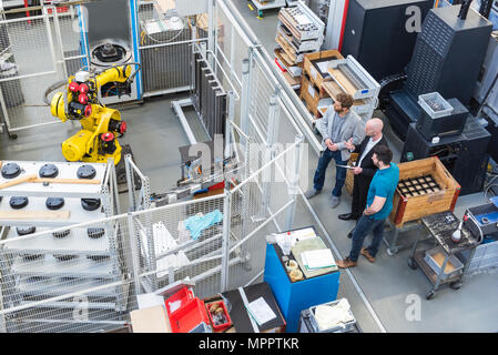 Businessman and employees discussing in modern factory Stock Photo