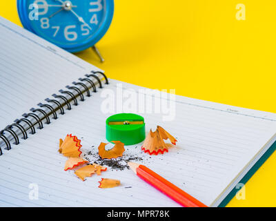 Office accessories including note book, red pencil, alarm clock and green sharpener on yellow background. Education and business concept. Stock Photo