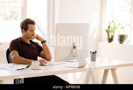 Businessman working on computer at home. Man sitting at his work table working on computer at home. Stock Photo