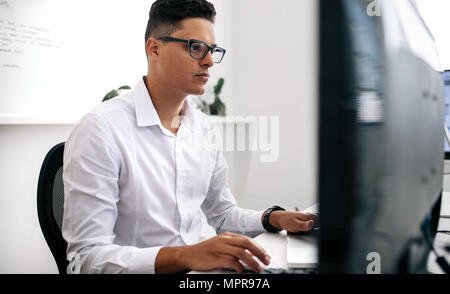 Software developer sitting in front of computer and working in office ...