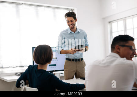 Businessman making a presentation to his colleagues in office. Office colleagues sharing lighter moments sitting at the conference room. Stock Photo
