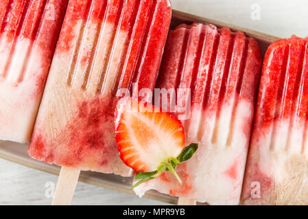Homemade Vegan Strawberry Popsicle from Strawberry Juice and Coconut Milk on light wooden background. Summer food concept. Top view. Stock Photo