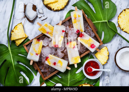 Pina Colada popsicles with candied cherries and pineapple on leaf Stock Photo